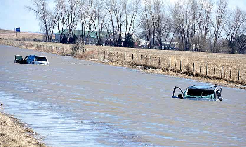 Two abandoned cars are submerged next to I-29 near Jefferson, South Dakota, after record flooding in March.