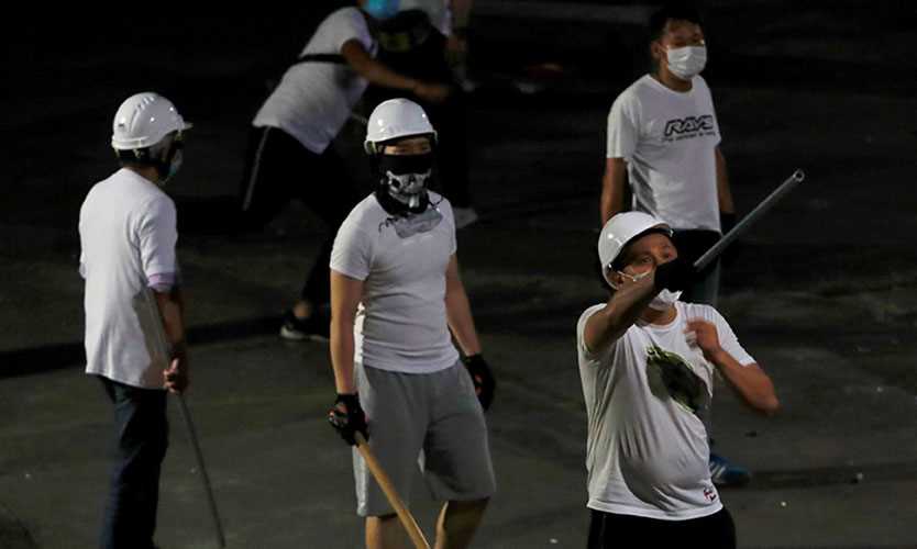 Men in white T-shirts with poles are seen in Yuen Long after attacking anti-extradition bill demonstrators at a train station in Hong Kong